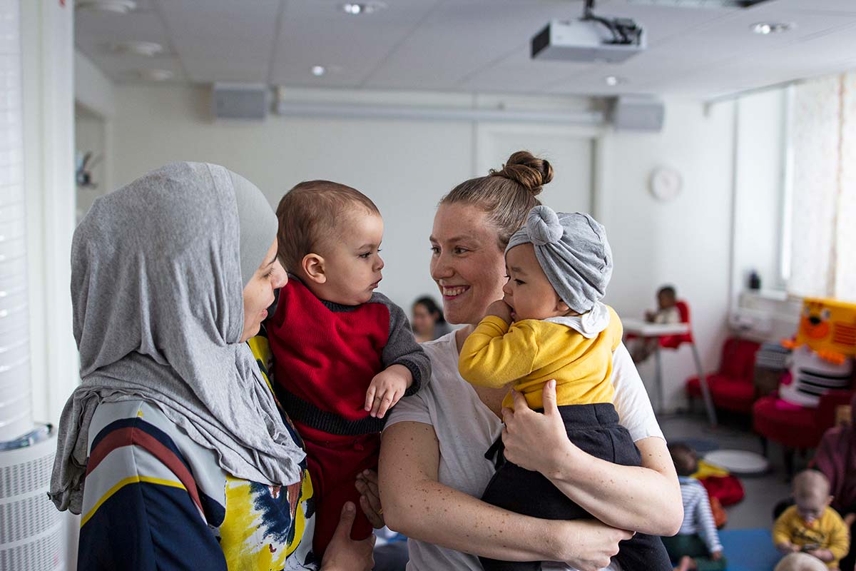 Two women with babies talking during a parents' meeting.